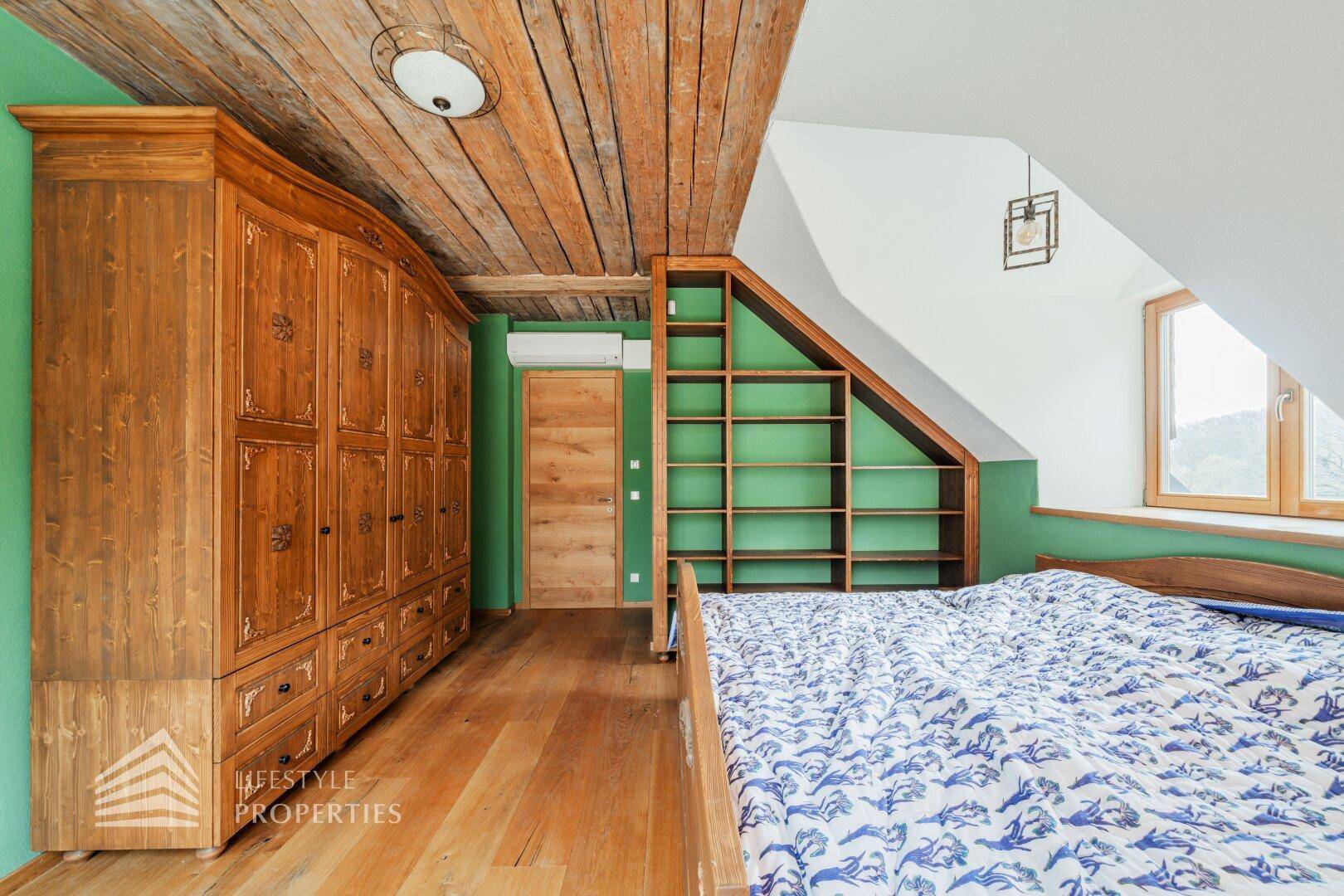 Schlafzimmer mit grünen Wänden, Holzboden und rustikalen Holzmöbeln unter Dachschräge.