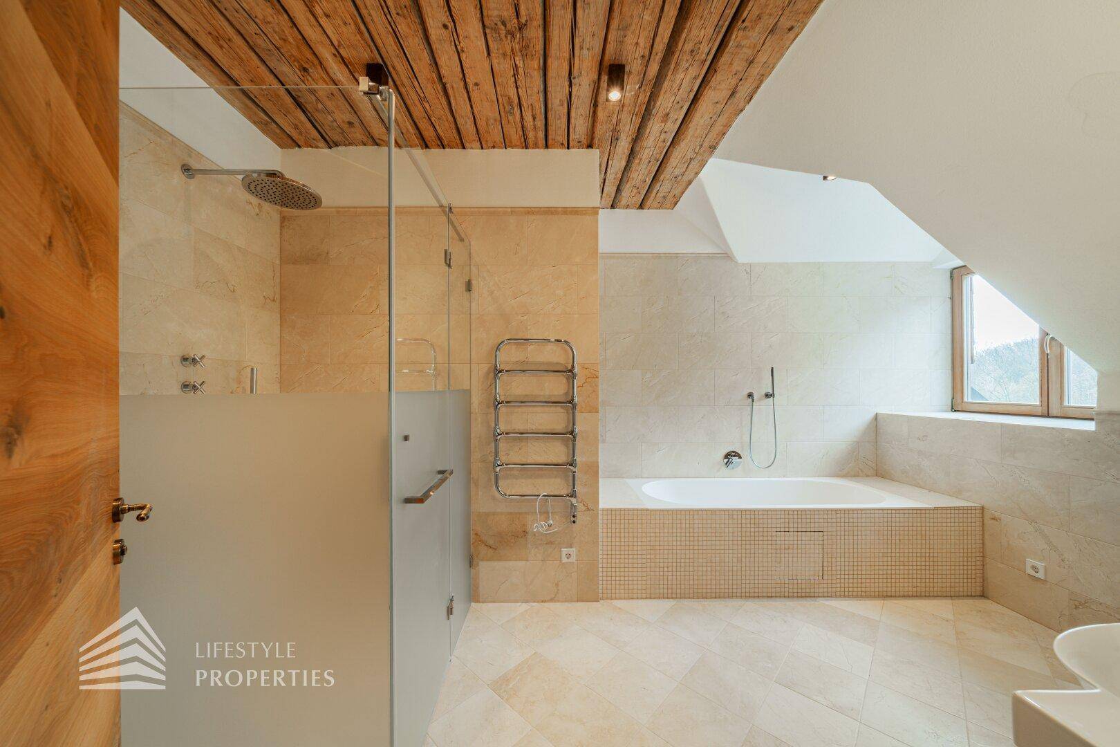 Modernes Badezimmer mit beigen Fliesen, Badewanne, Dusche und Holzdecke.