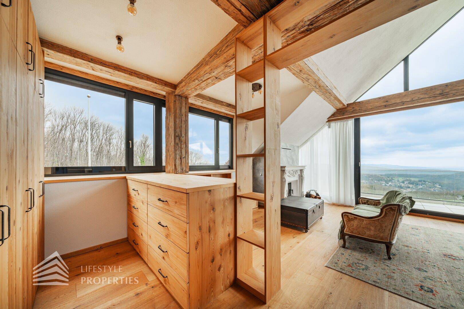 Schlafzimmerbereich mit Holzeinbauten, Fenstern und Blick auf die umliegende Landschaft.