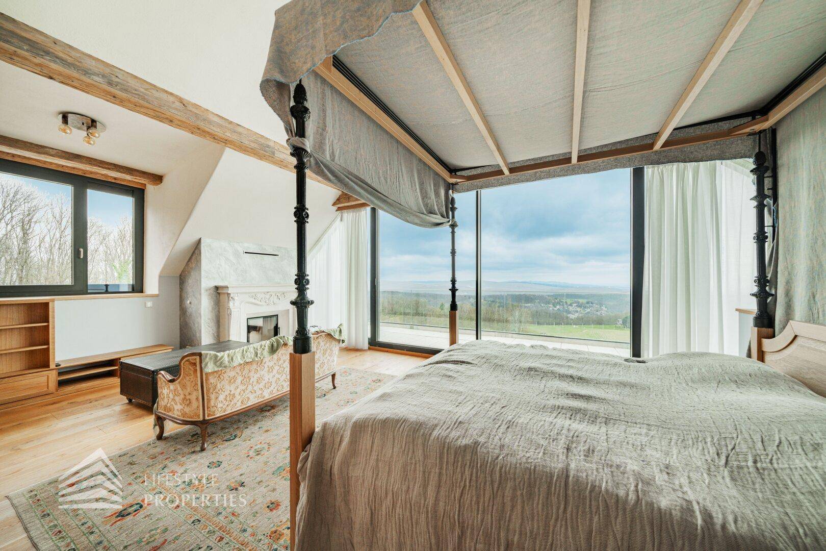 Gemütliches Schlafzimmer mit Himmelbett und großen Fenstern, die einen weiten Blick auf die Landschaft bieten.