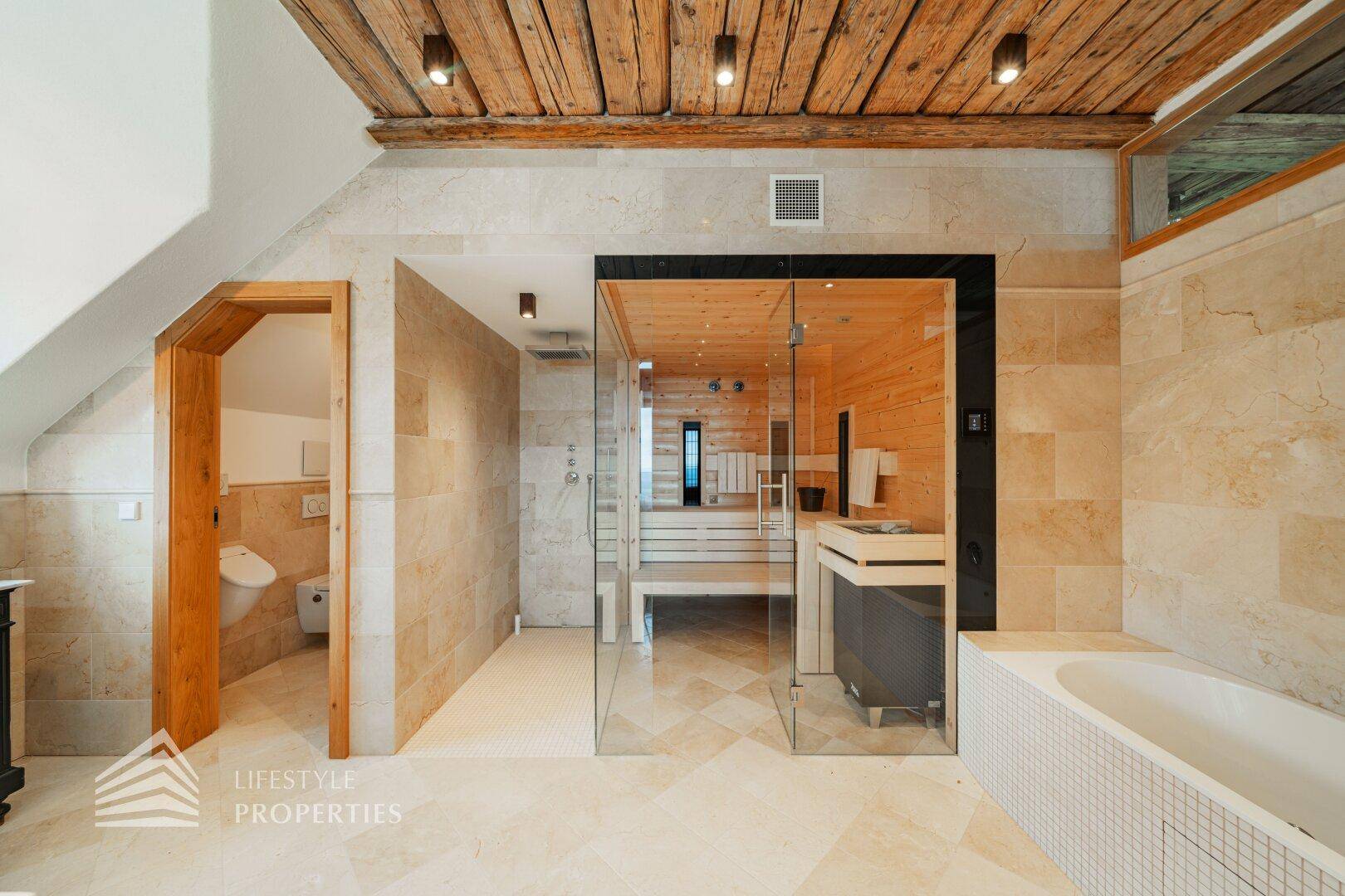 Luxuriöses Badezimmer mit Sauna, Dusche, Badewanne und beigen Fliesen.