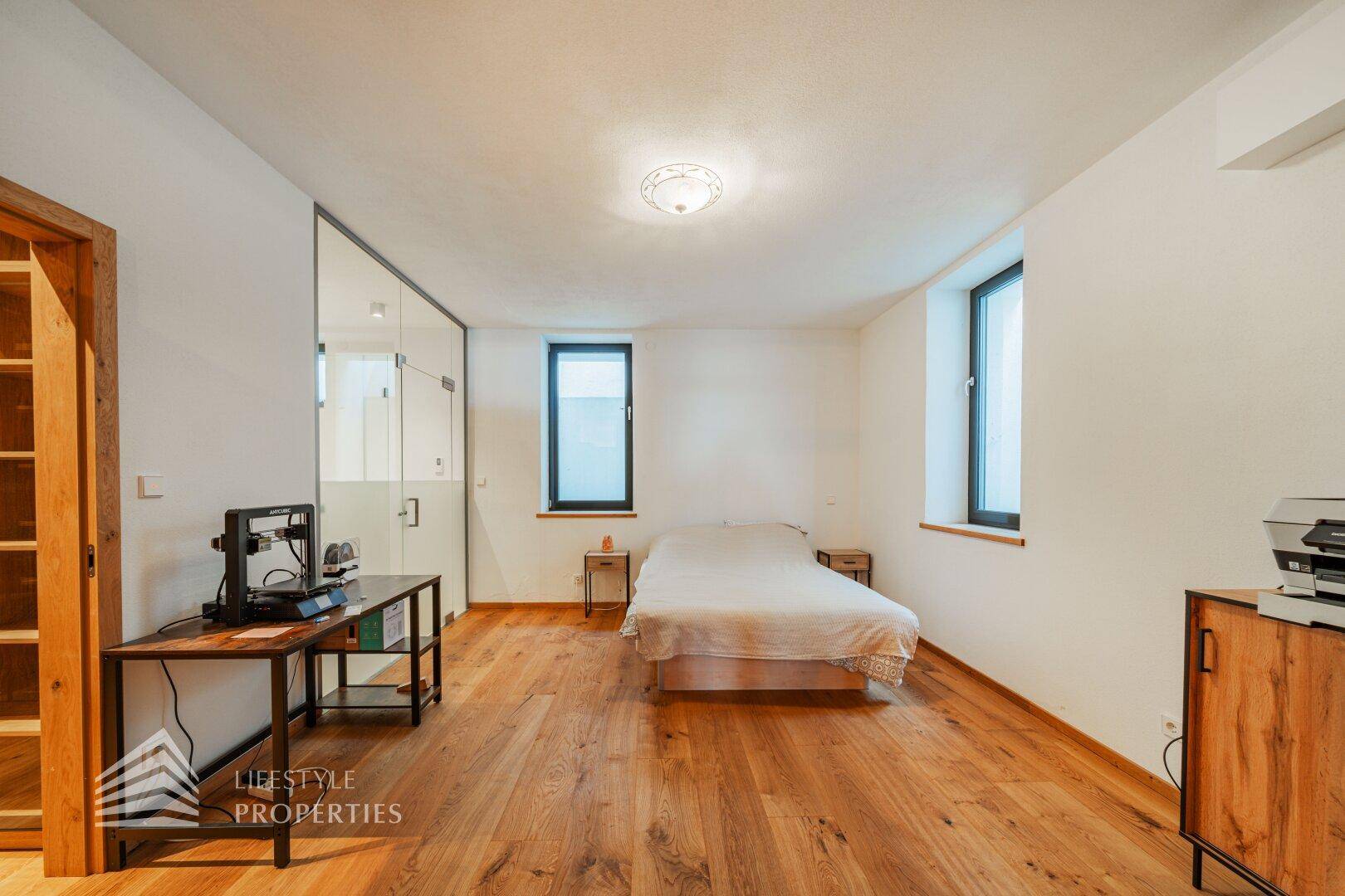 Schlafzimmer mit Holzboden, weißem Bett und modernen Möbeln.