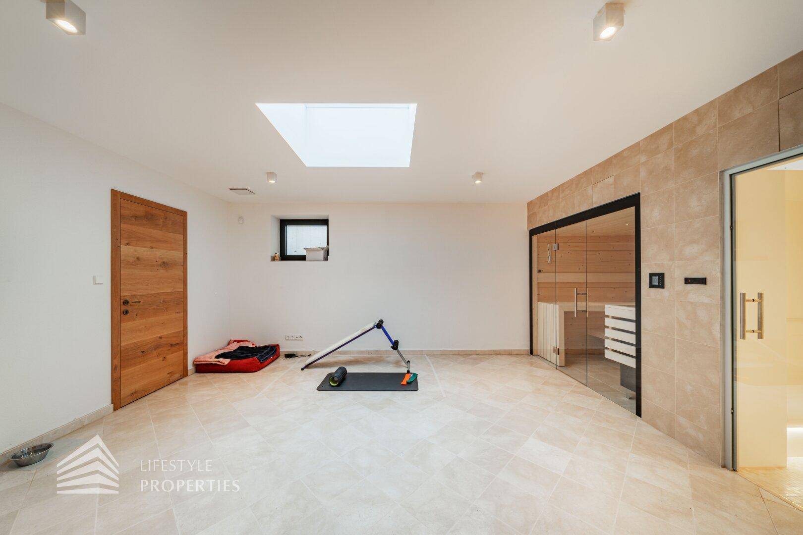 Geräumiger Fitnessraum mit Sauna, kleinem Fenster und viel Platz für Sportaktivitäten und Erholung.