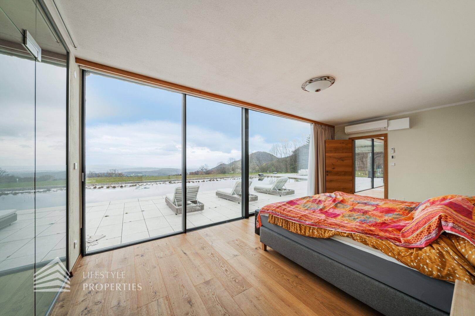 Modernes Schlafzimmer mit Holzboden, Klimaanlage und Zugang zu einer großen Terrasse.