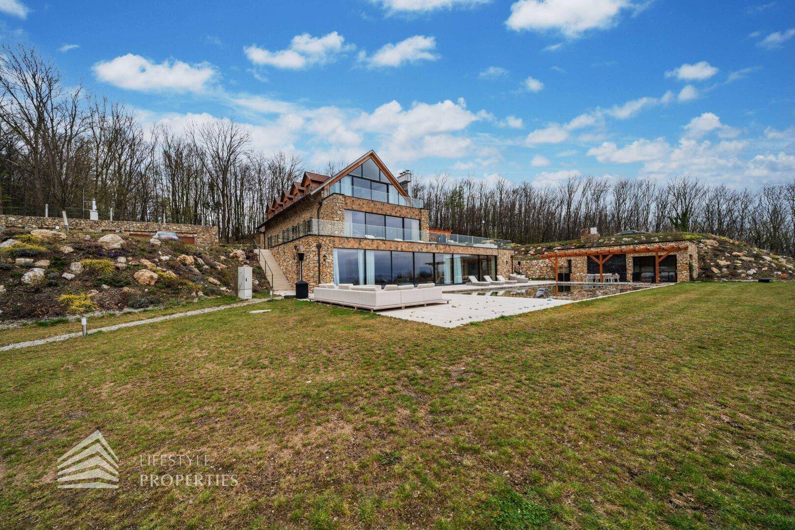 Beeindruckende Villa in weitläufiger Grünanlage mit Pool und umgeben von Wald und Hügeln.