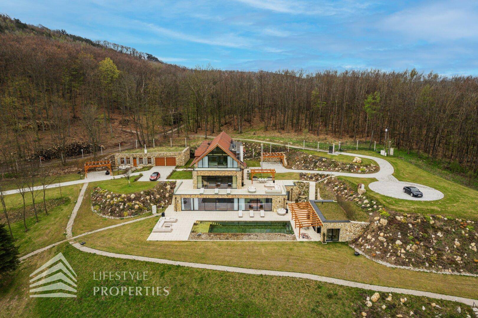 Gesamtaufnahme des luxuriösen Anwesens mit Haupthaus, Nebengebäude, Pool und weitläufigem Grundstück.