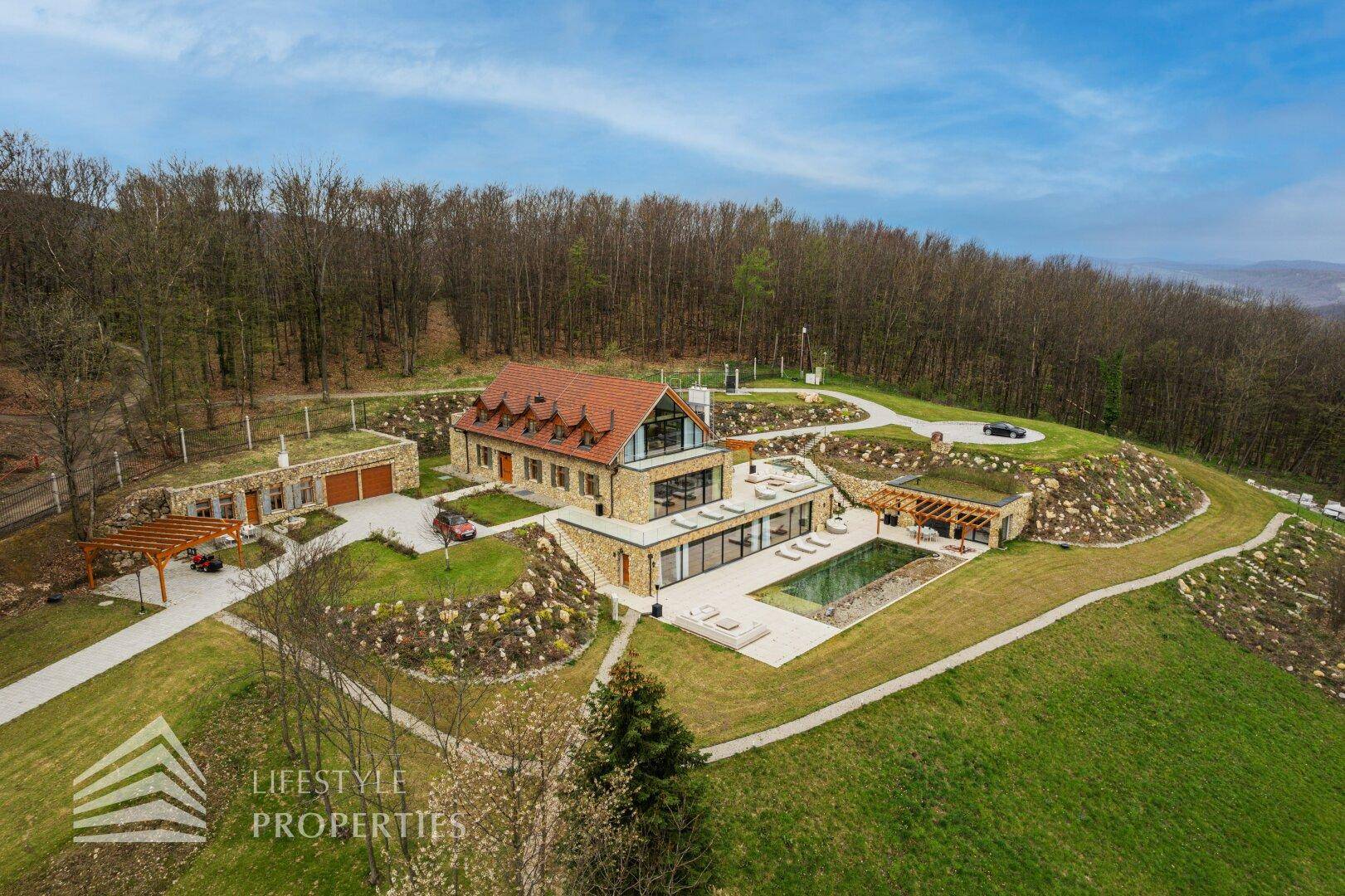 Umfassende Luftaufnahme des Anwesens mit Hauptvilla, Pool, Garage und weitläufigen Grünflächen.