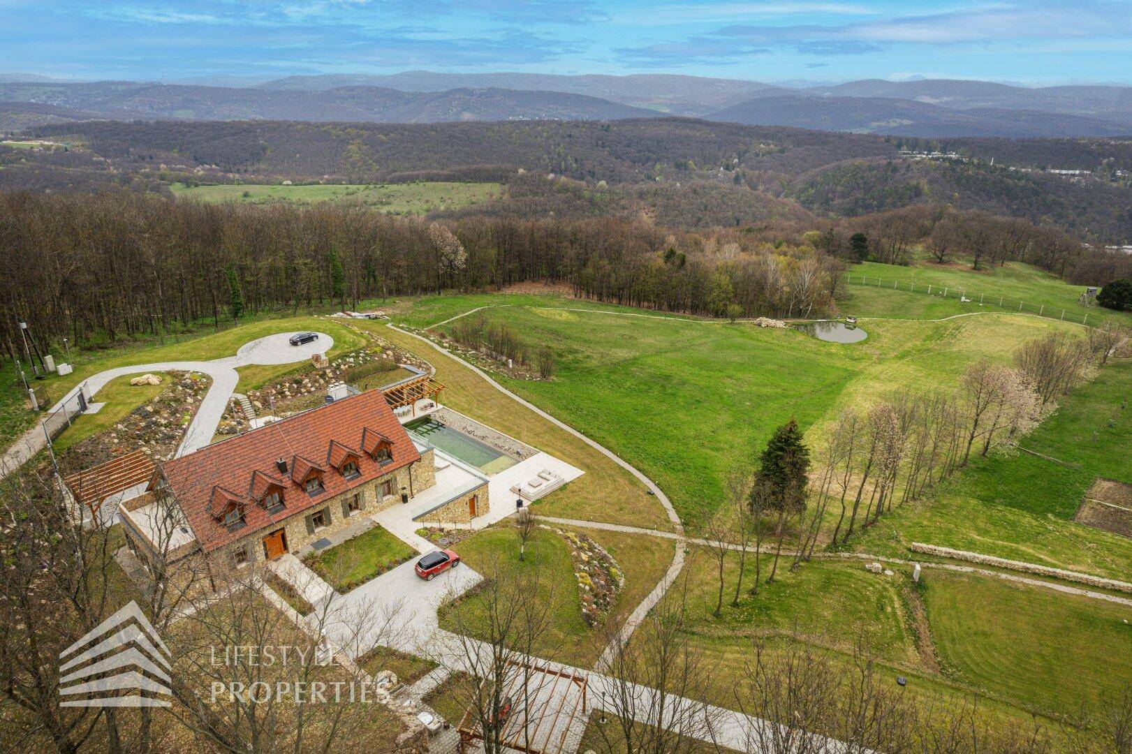 Weitläufige Luftaufnahme des Anwesens mit Villa, Pool und den umliegenden Feldern und Wäldern.
