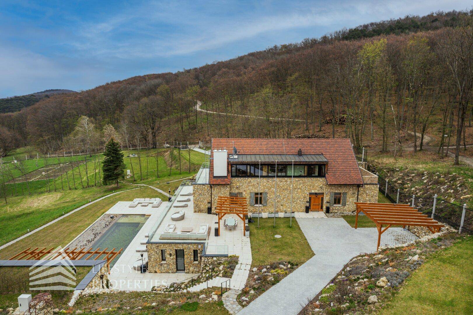 Luftaufnahme eines luxuriösen Anwesens mit Pool, weitläufigem Garten und bewaldeter Umgebung.