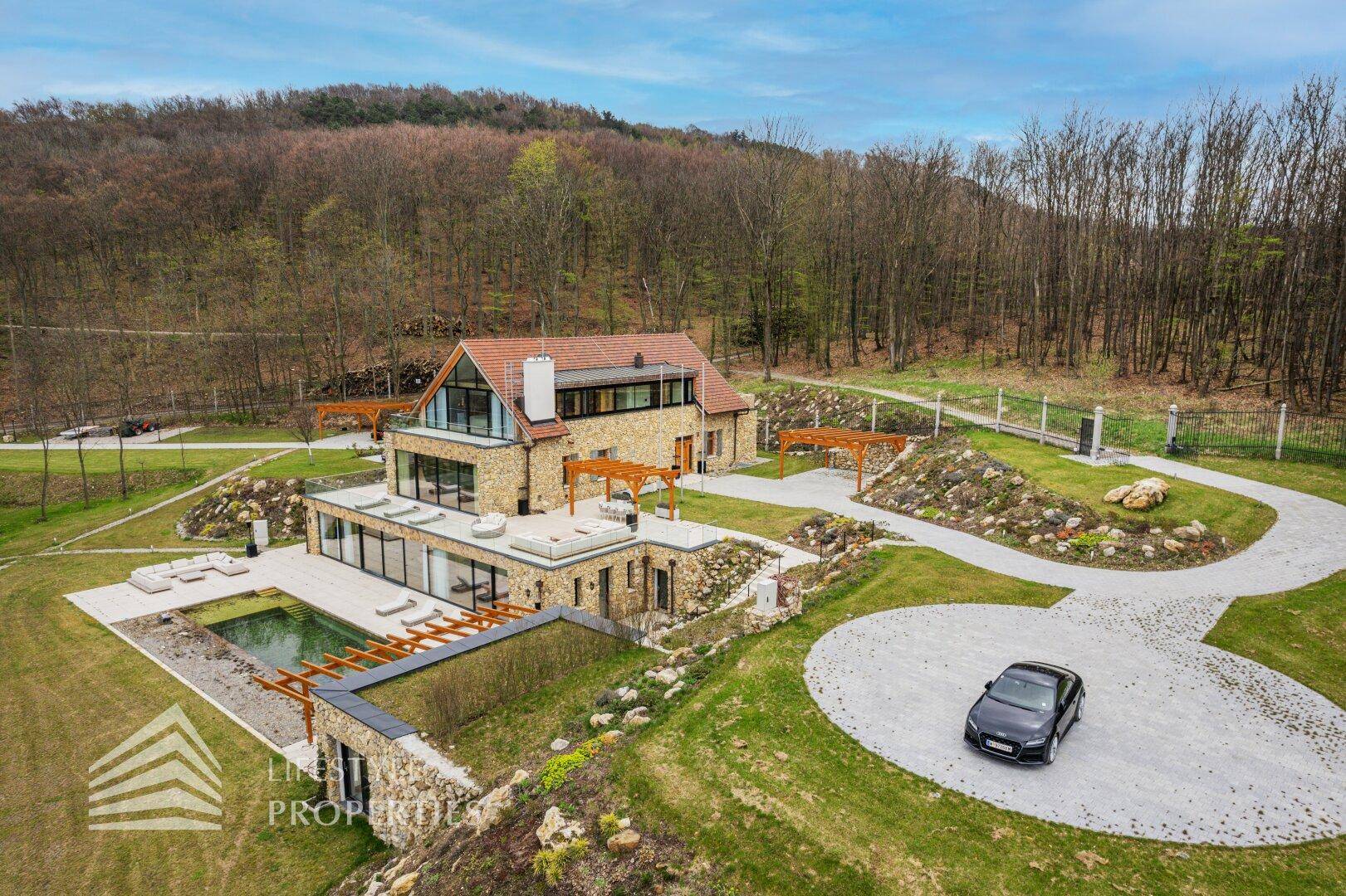 Weitläufiges Anwesen mit moderner Architektur, Pool, gepflegtem Garten und Zufahrt in idyllischer Lage.