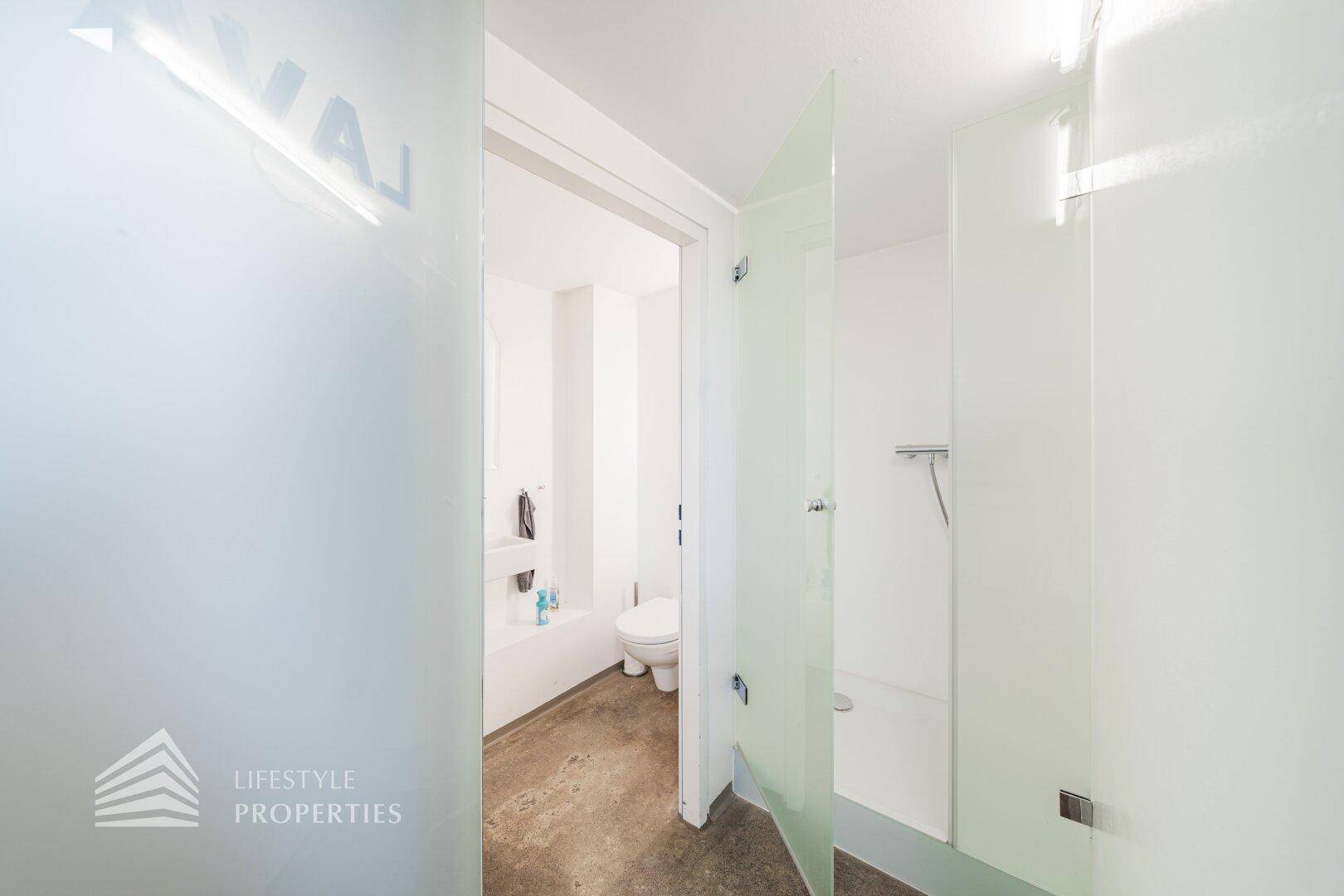 Modernes Badezimmer mit Milchglastür, Dusche und WC in minimalistischem Design.