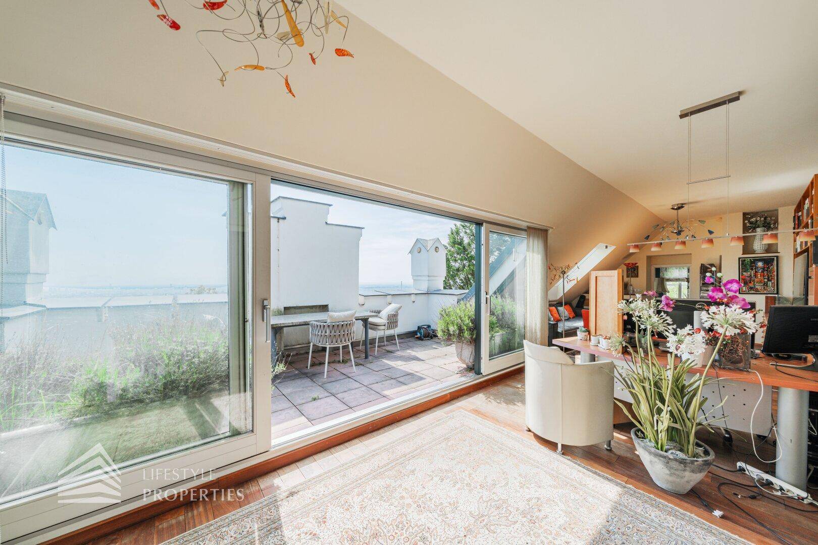 Heller Raum im Dachgeschoss mit großen Schiebetüren, die zu einer privaten Dachterrasse führen.
