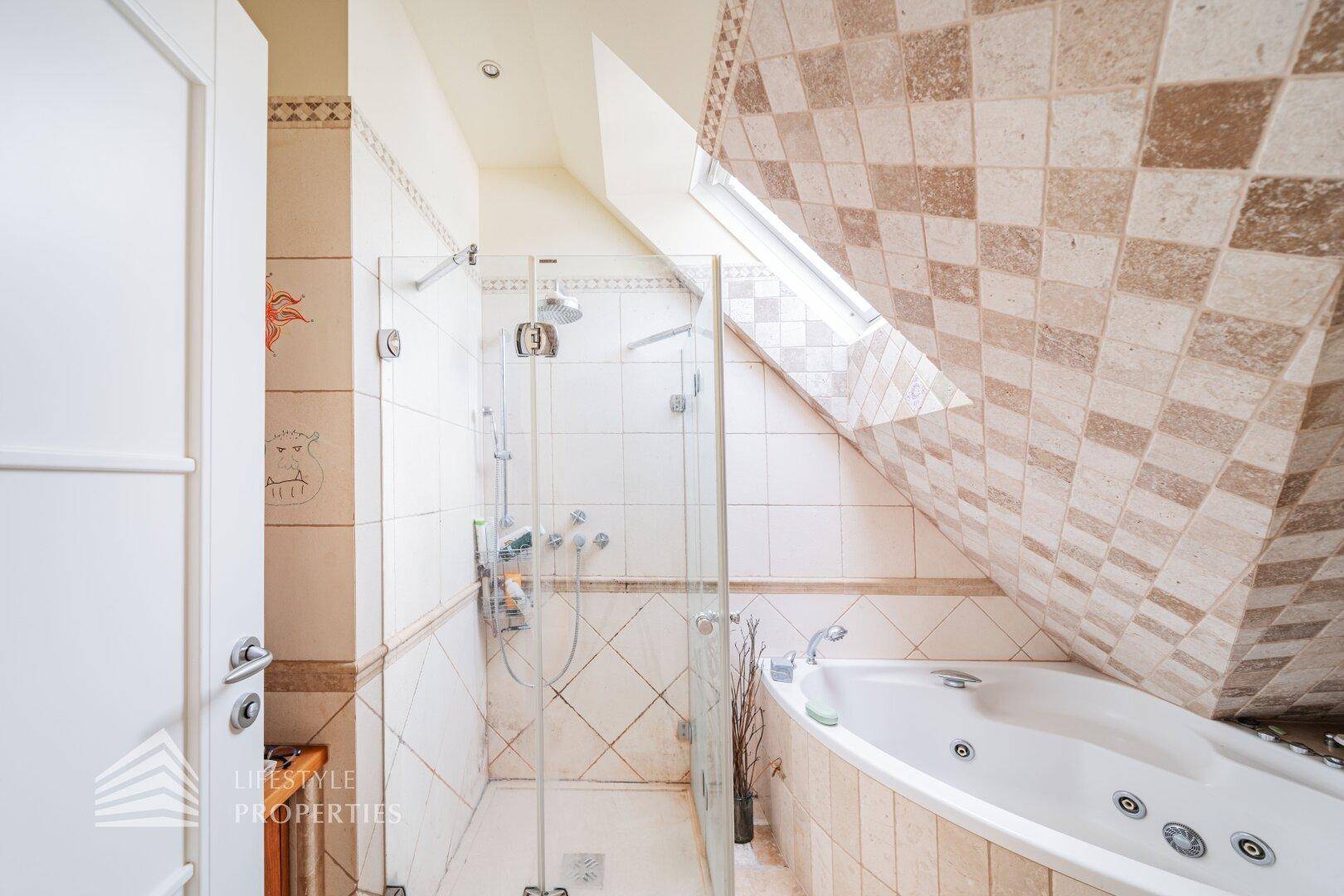 Dachgeschoss-Badezimmer mit Whirlpool-Badewanne, Dusche und schrägen Wänden.