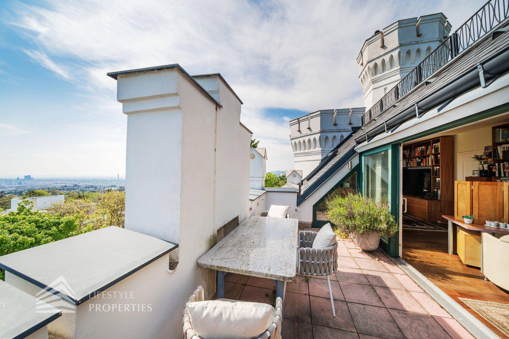 Geräumige Terrasse mit Sitzgelegenheiten und weitem Blick über die Stadt und die umliegende Landschaft.