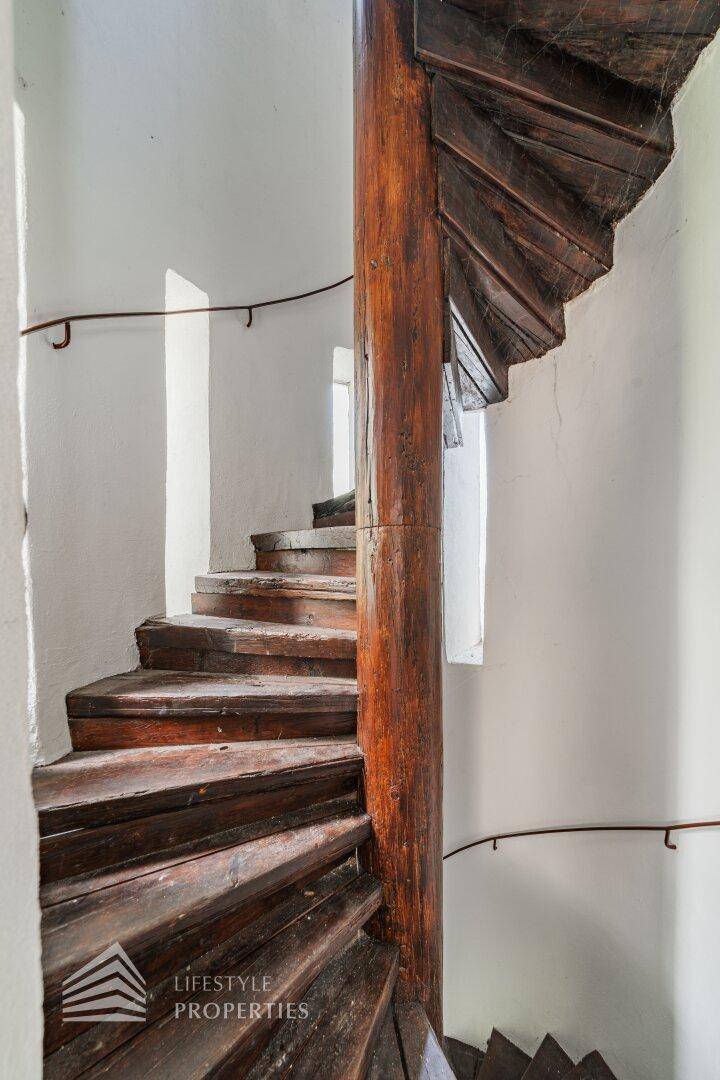 Historische Wendeltreppe aus Holz mit Handlauf und natürlichem Lichteinfall.
