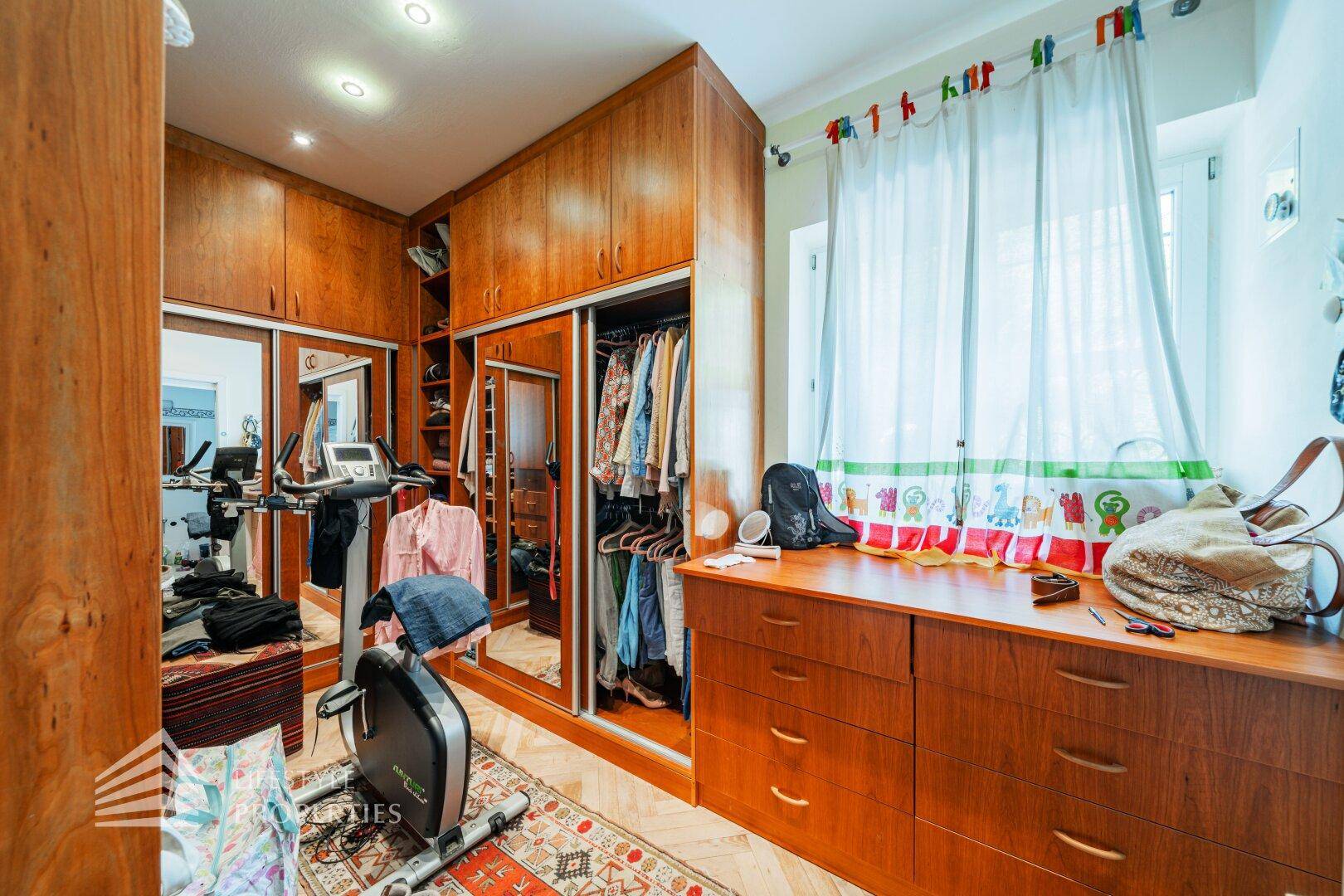 Ankleidezimmer mit Einbauschränken, Spiegeln und Fitnessgeräten.