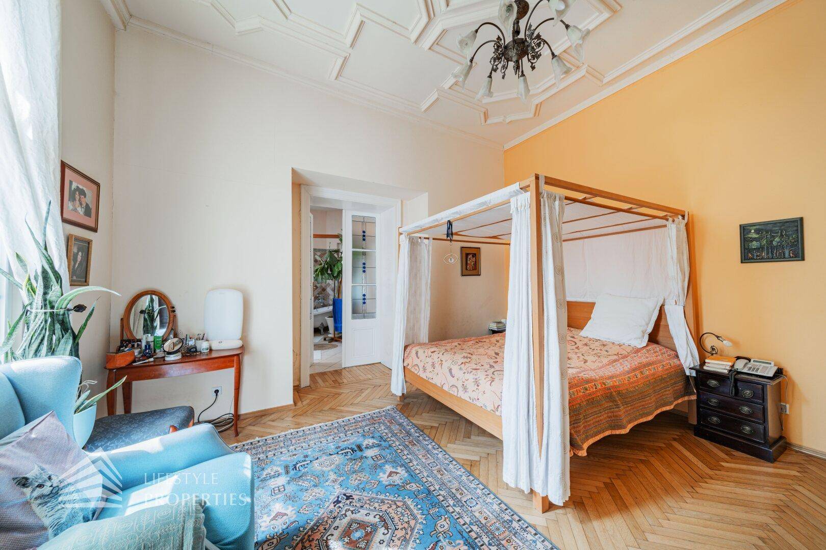 Geräumiges Schlafzimmer mit Himmelbett, Fischgrätparkett und Stuckdecke.