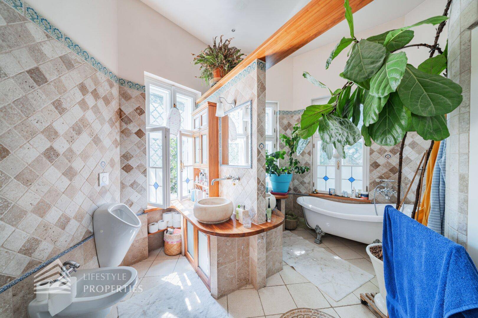 Großes Badezimmer mit freistehender Badewanne, Urinal und gemusterten Fliesen.
