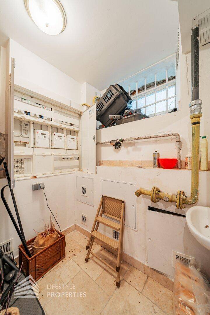 Hauswirtschaftsraum mit Zählerkasten, Rohren und Fliesenboden.