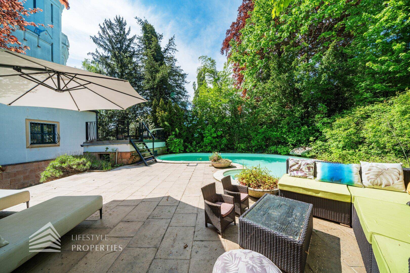 Sonniger Gartenbereich mit Pool, Lounge-Möbeln und viel Grün für Entspannung.