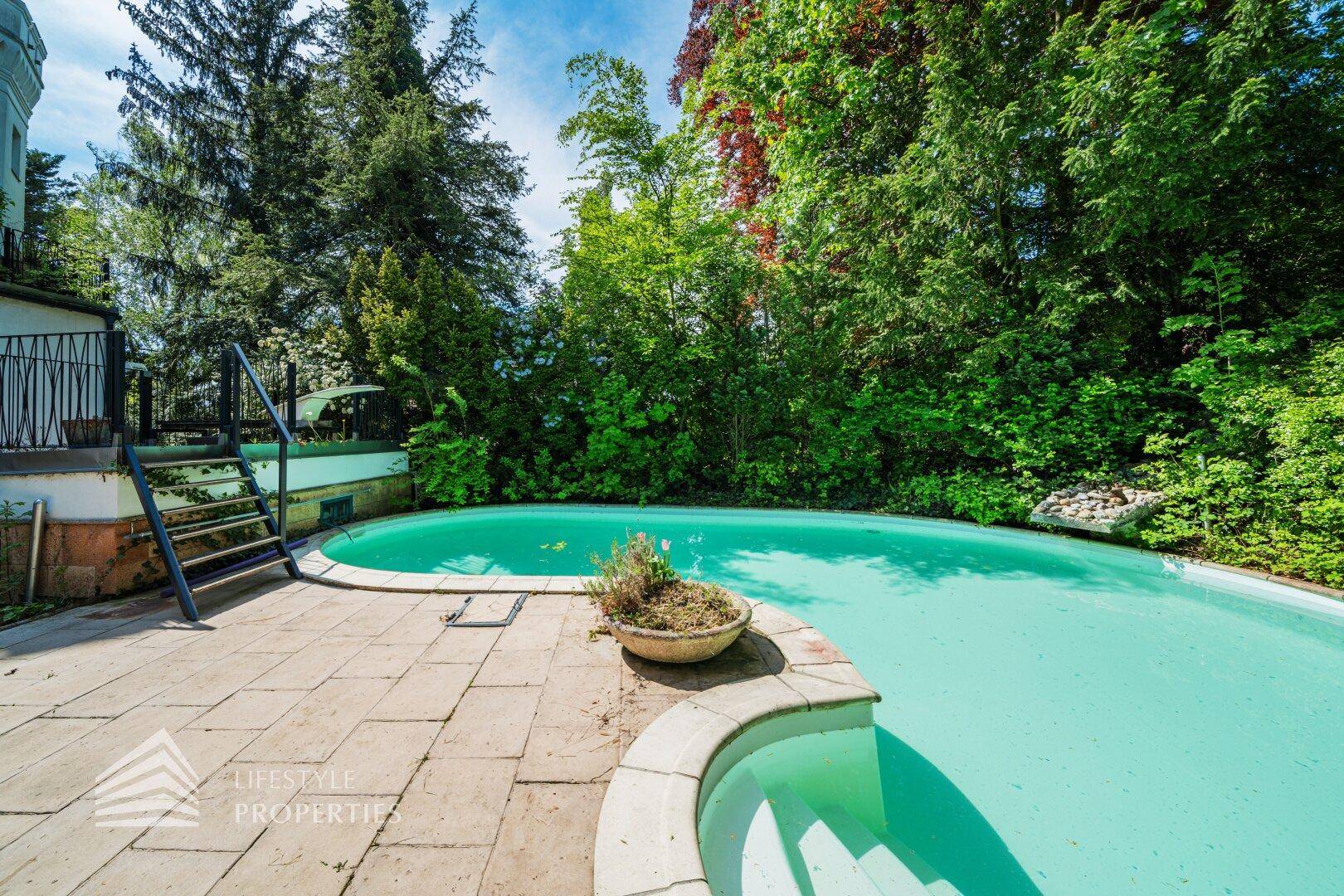 Erfrischender Poolbereich im Garten mit gepflasterter Terrasse und umgebender Natur.