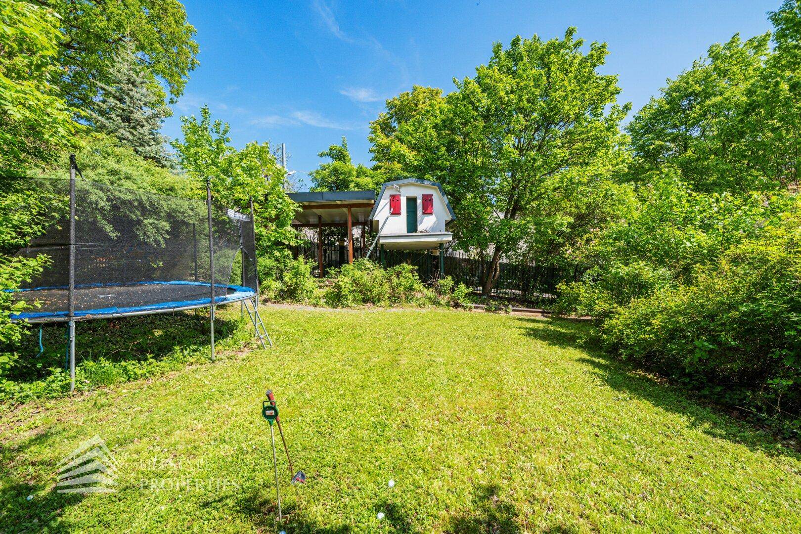 Großer Rasengarten mit Trampolin und Blick auf das charmante Gartenhaus.