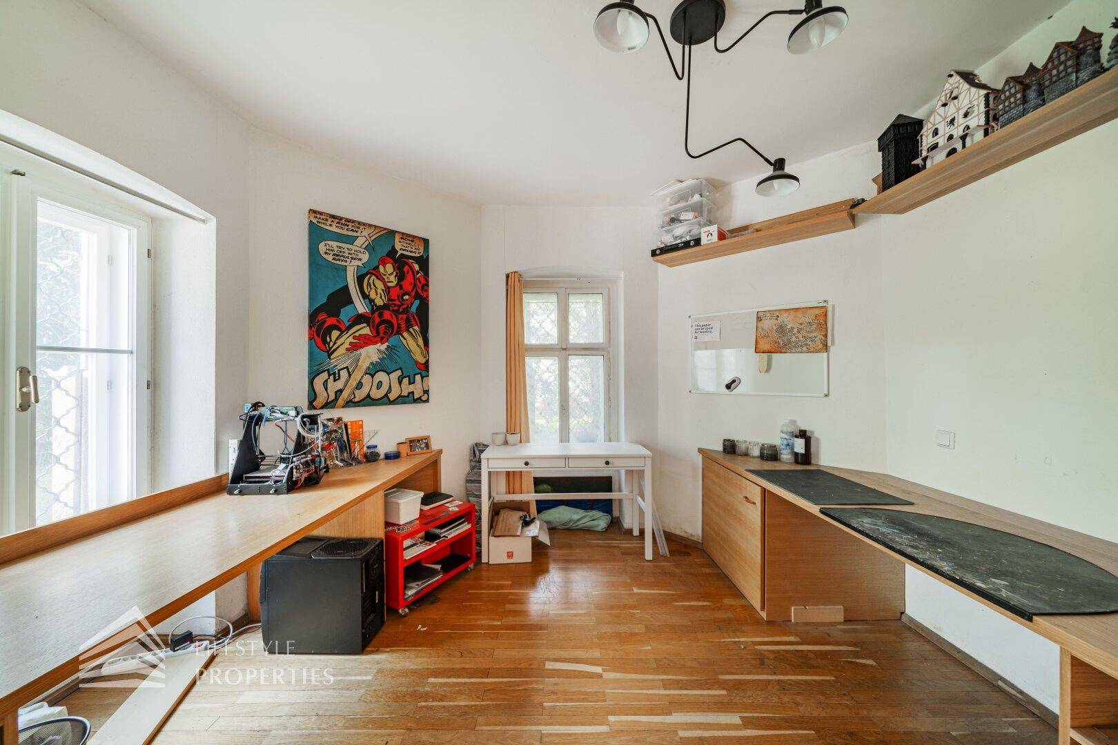 Helles Arbeitszimmer mit mehreren Schreibtischen und Holzboden.