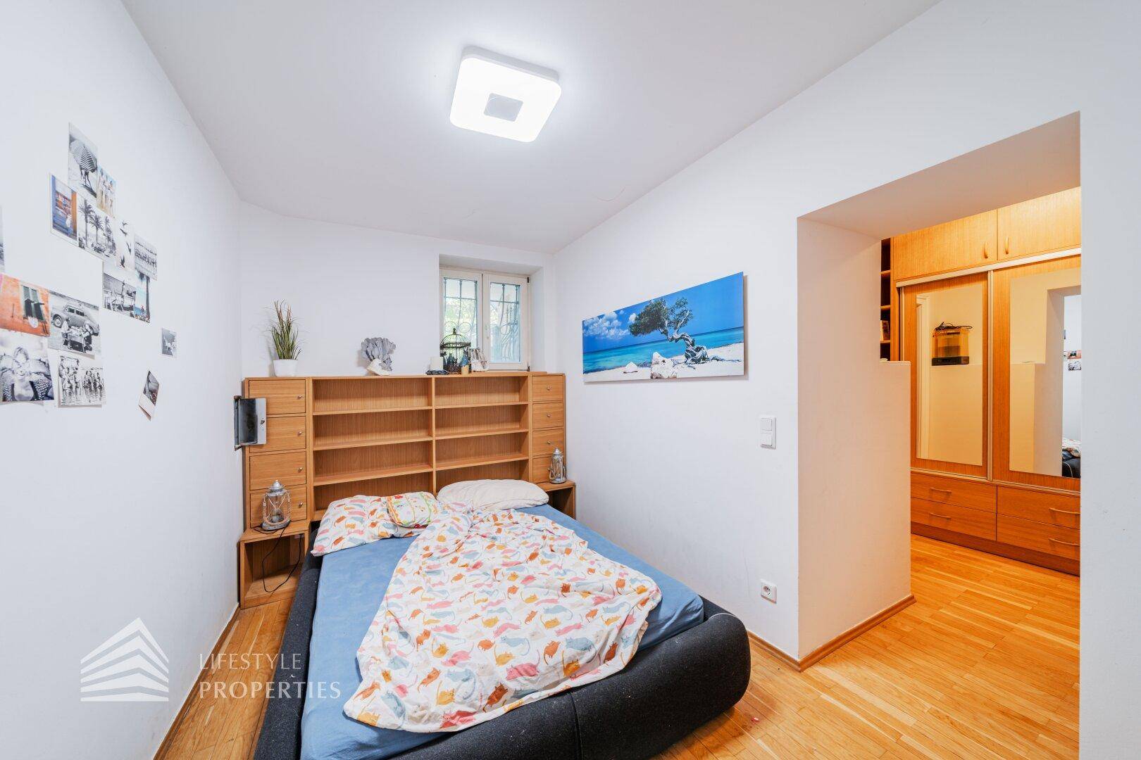 Gemütliches Schlafzimmer mit Holzbett, Regalen und Zugang zum Ankleidezimmer.