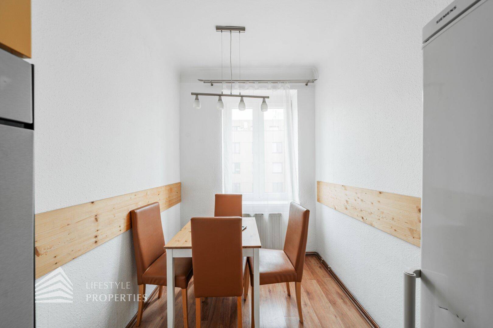 Heller Essbereich mit Holztisch und vier Stühlen am Fenster.