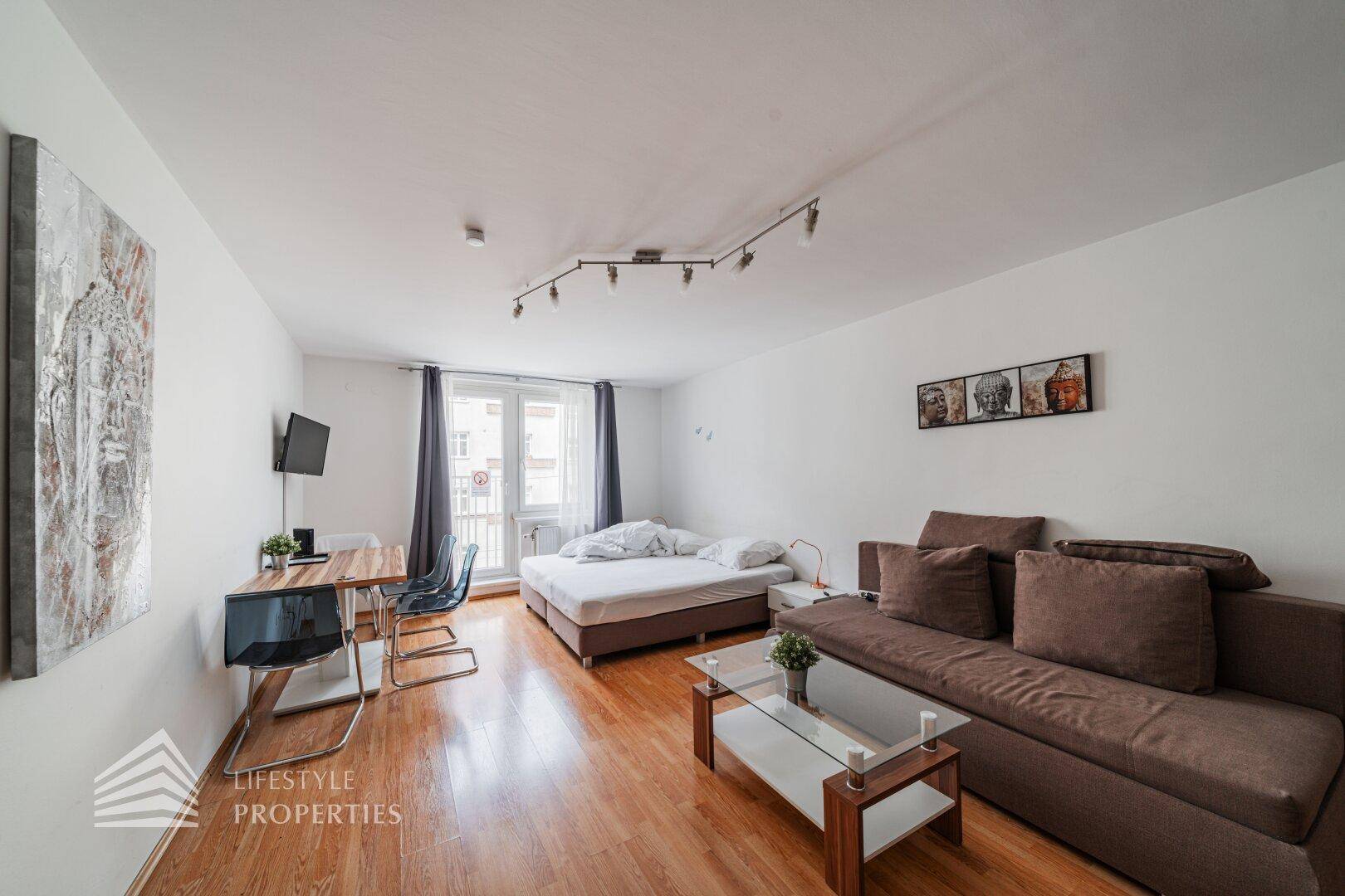 Geräumiger Wohnbereich mit Schlafsofa, Doppelbett und Essbereich, ideal für ein Studio-Apartment.