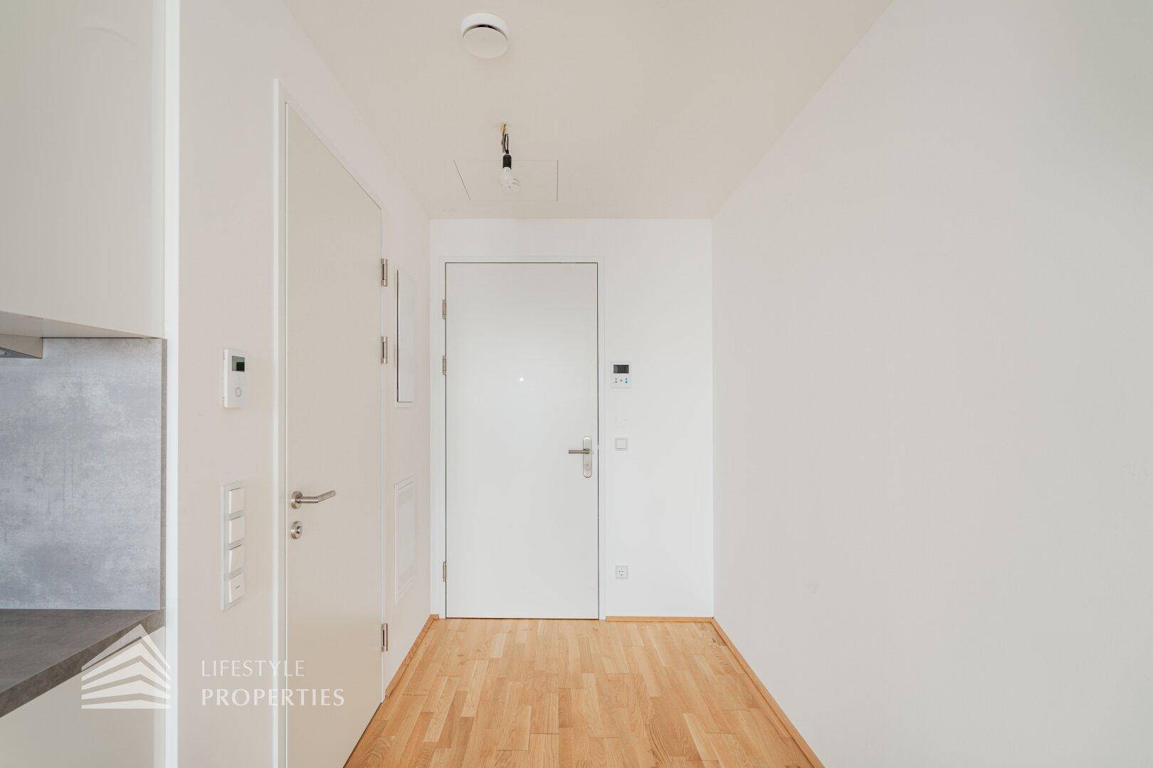 Heller Eingangsbereich mit Holzboden und modernen Türen, führt in die Wohnräume.