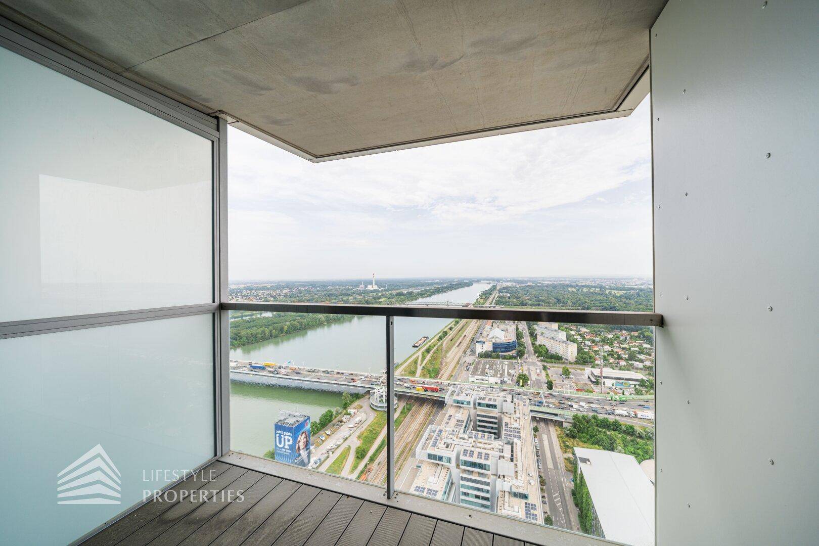 Moderner Balkon mit Glasbrüstung und weitem Blick über die Stadt und den Fluss.