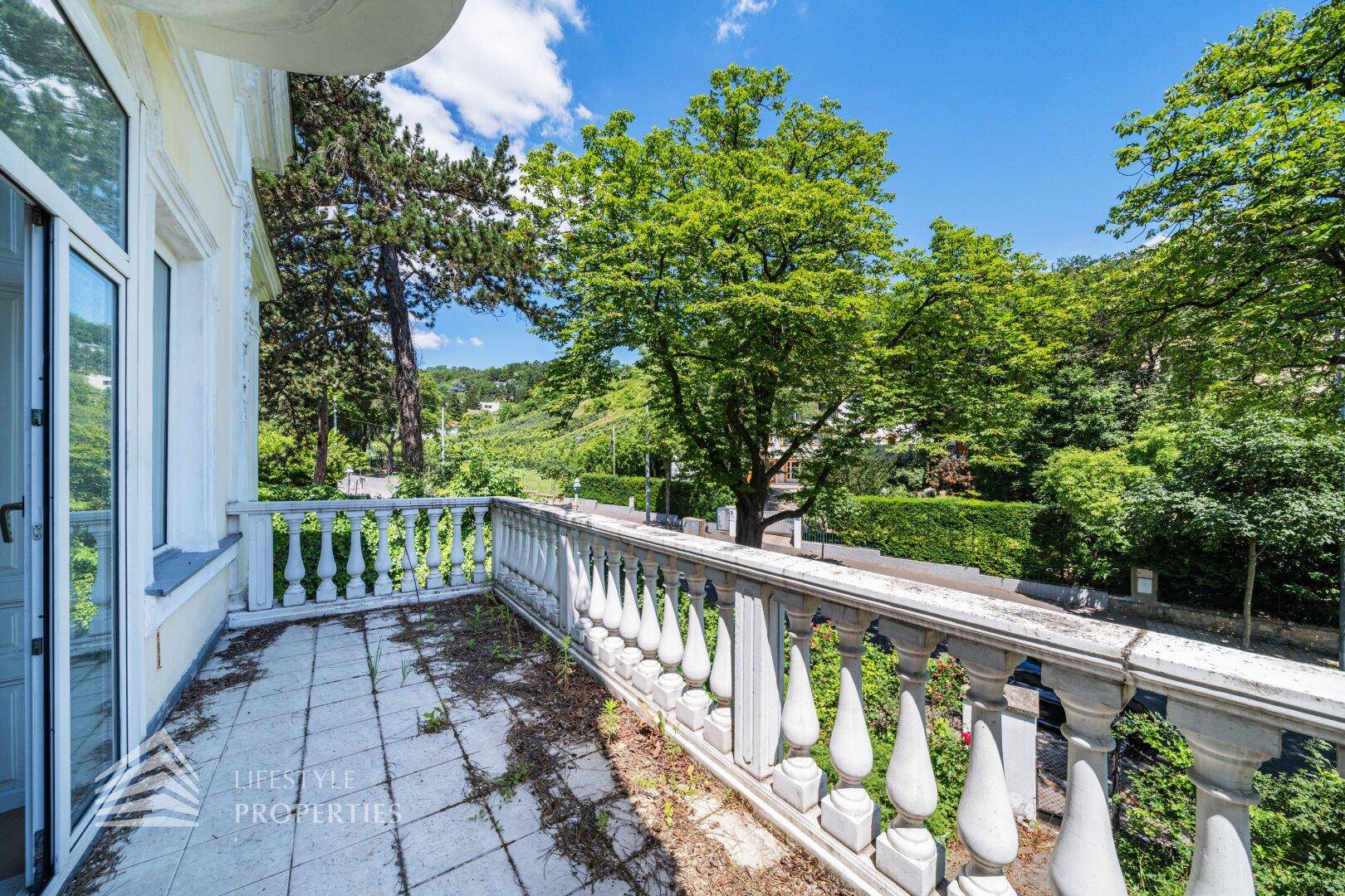 Breiter Balkon mit Balustrade und weitem Blick über die grüne Umgebung.