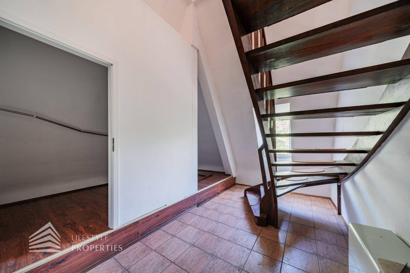 Holztreppe zum Dachgeschoss mit integriertem Stauraum unter der Schräge.