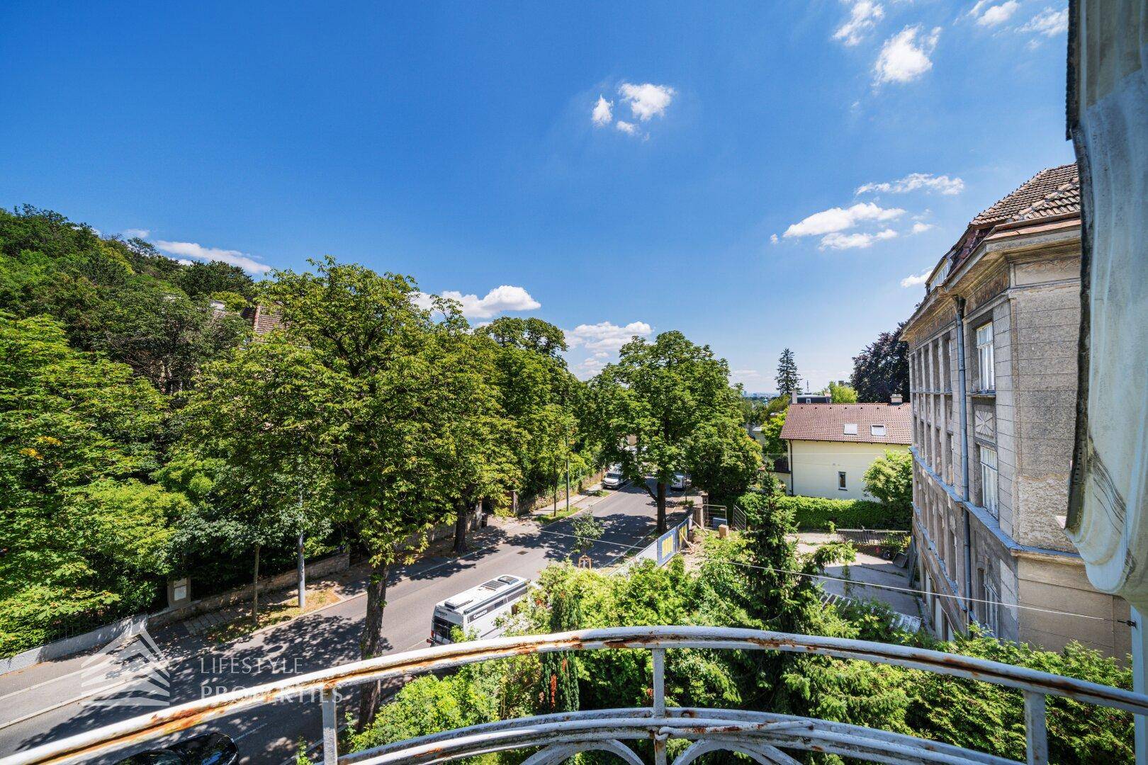 Weitblick von einem französischen Balkon über die Baumwipfel und die Straße.