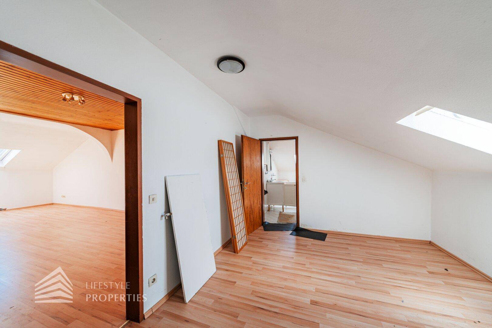 Helles Dachzimmer mit Laminatboden und Dachfenster, bereit zur Nutzung.