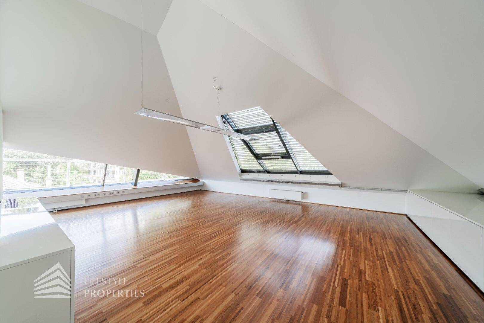 Offener Raum mit einzigartiger Architektur, schrägen Decken und großen Fenstern, die eine helle Atmosphäre schaffen.