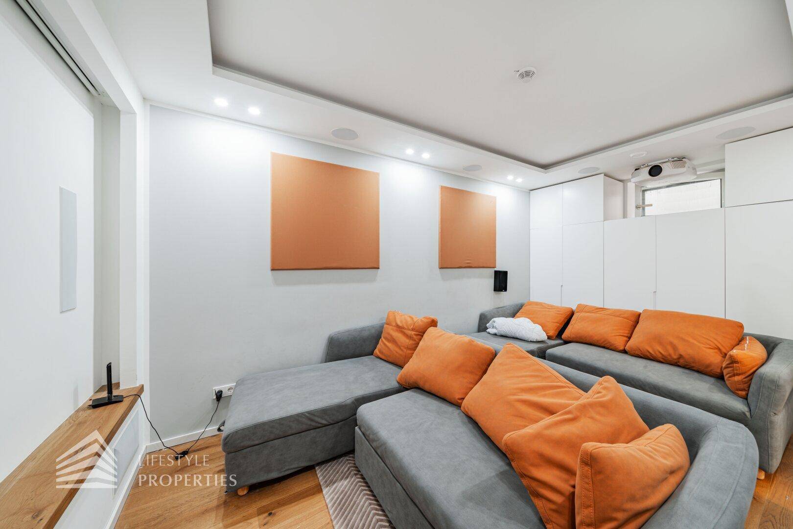 Gemütlicher Medienraum mit großem Sofa, Projektor und Holzboden für entspannte Abende.