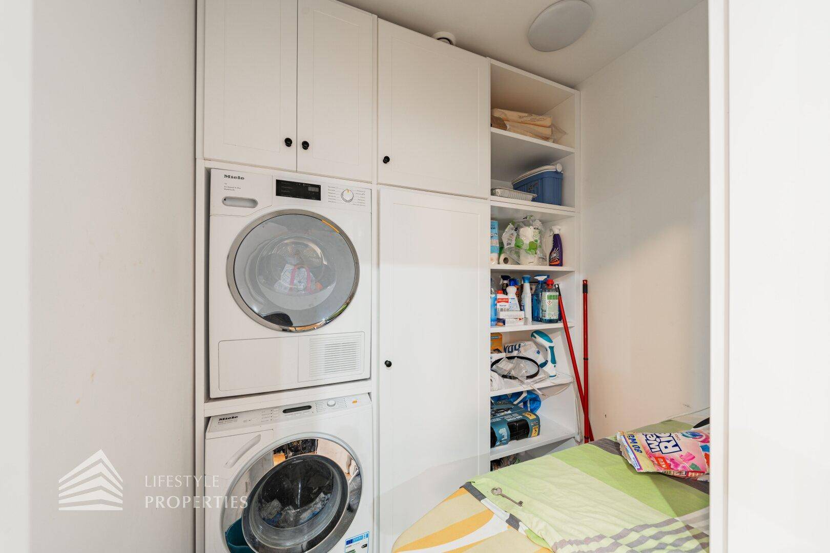 Praktischer Hauswirtschaftsraum mit Waschmaschine, Trockner und integriertem Stauraum.