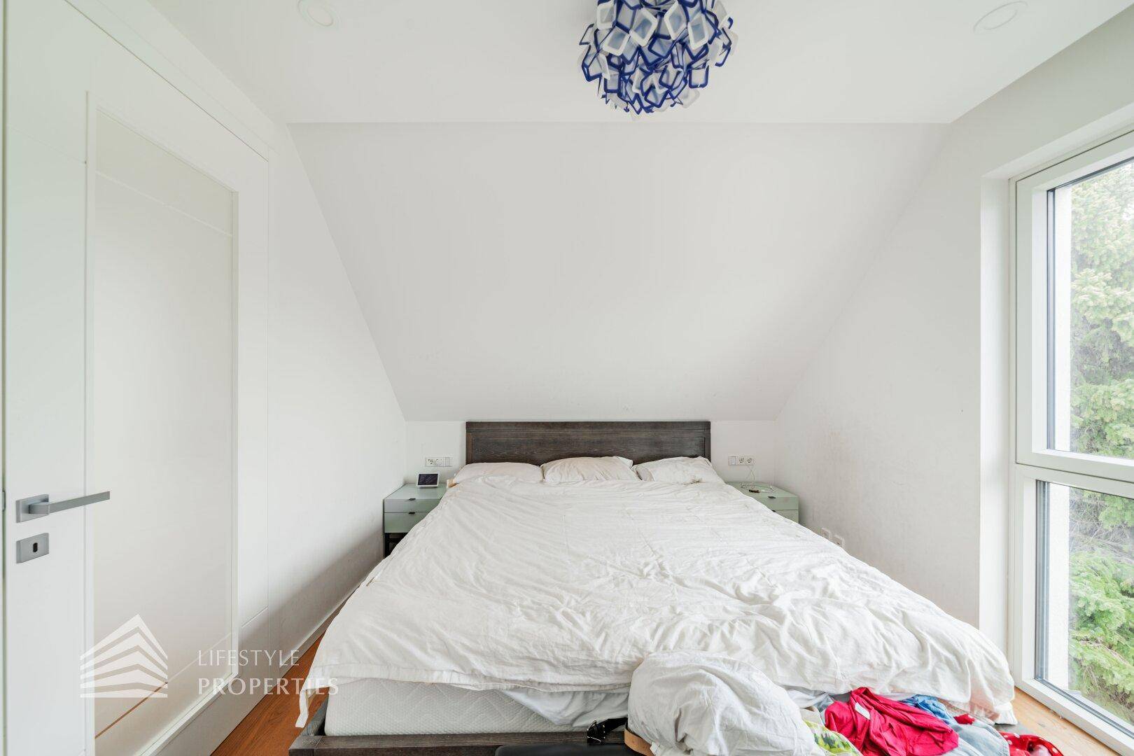 Gemütliches Schlafzimmer im Dachgeschoss mit schrägen Wänden und Holzboden.