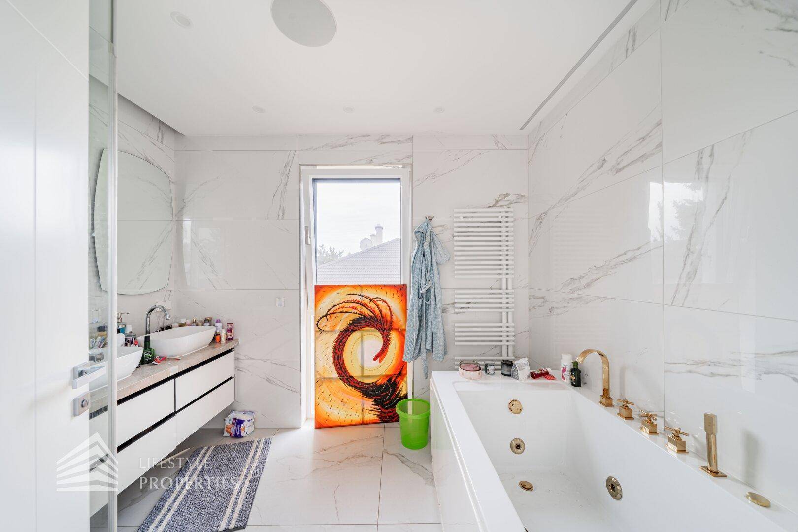 Modernes Badezimmer mit großer Badewanne, Doppelwaschbecken und Marmorfliesen.