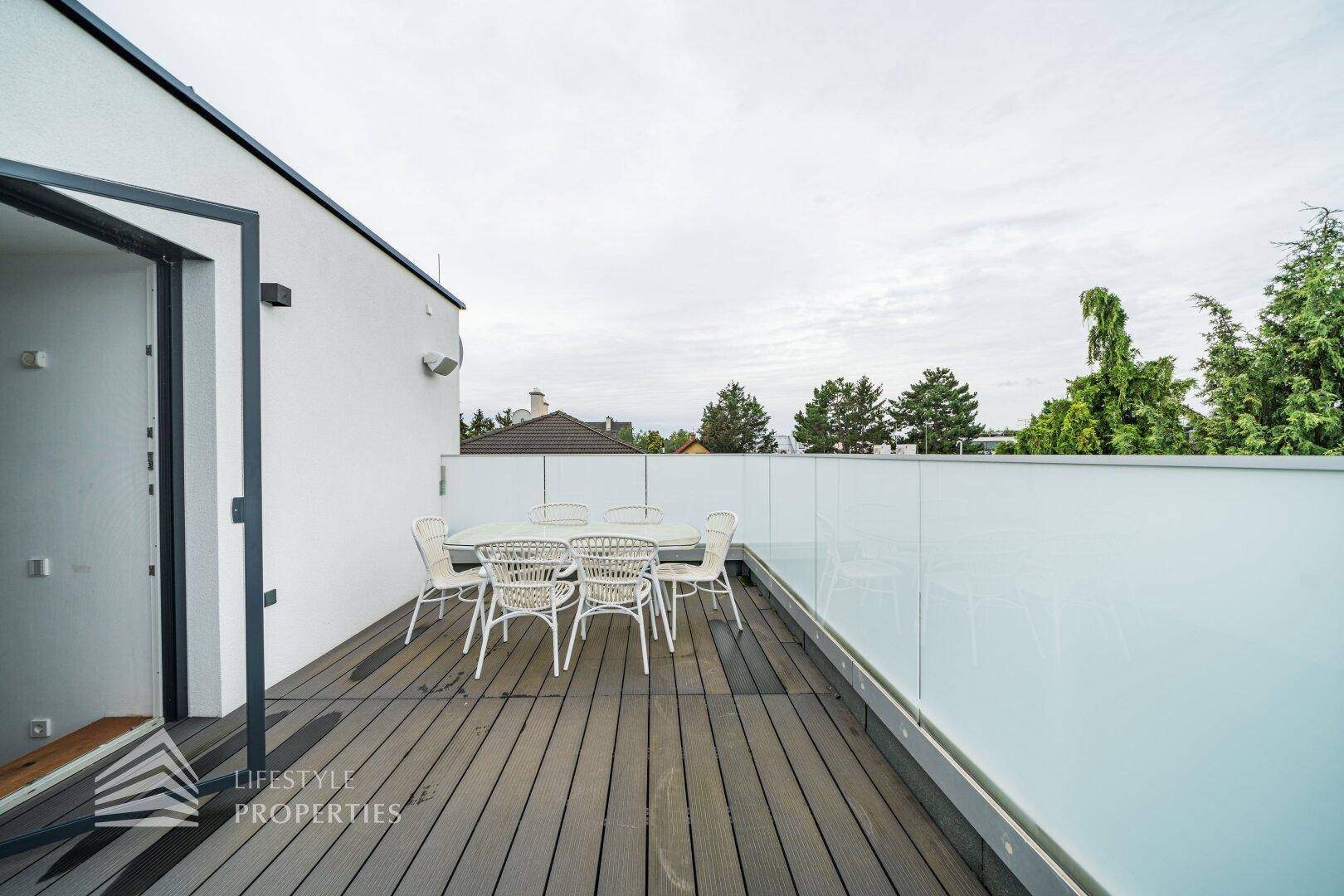 Geräumige Dachterrasse mit Holzboden und modernen Glasgeländern, möbliert für Entspannung.