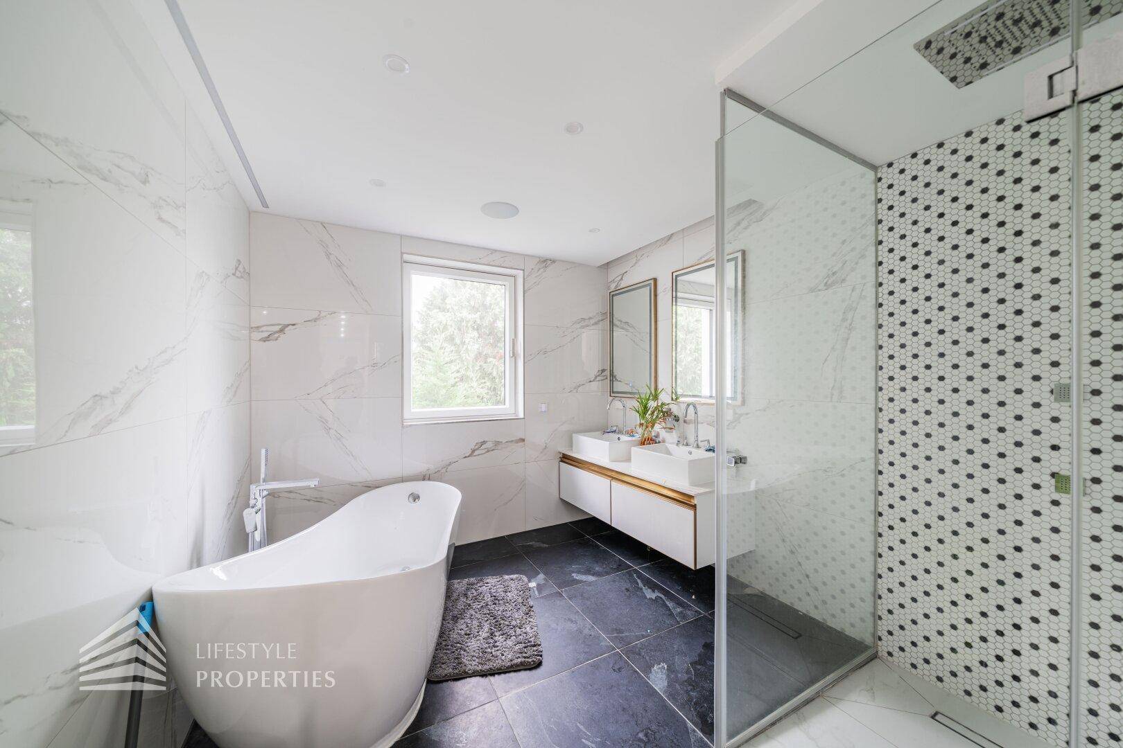 Luxuriöses Badezimmer mit freistehender Badewanne, Doppelwaschbecken und großer Duschkabine.