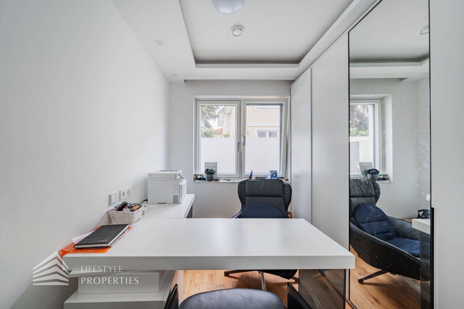 Helles Arbeitszimmer mit großem Schreibtisch, Spiegelschrank und Blick ins Grüne.
