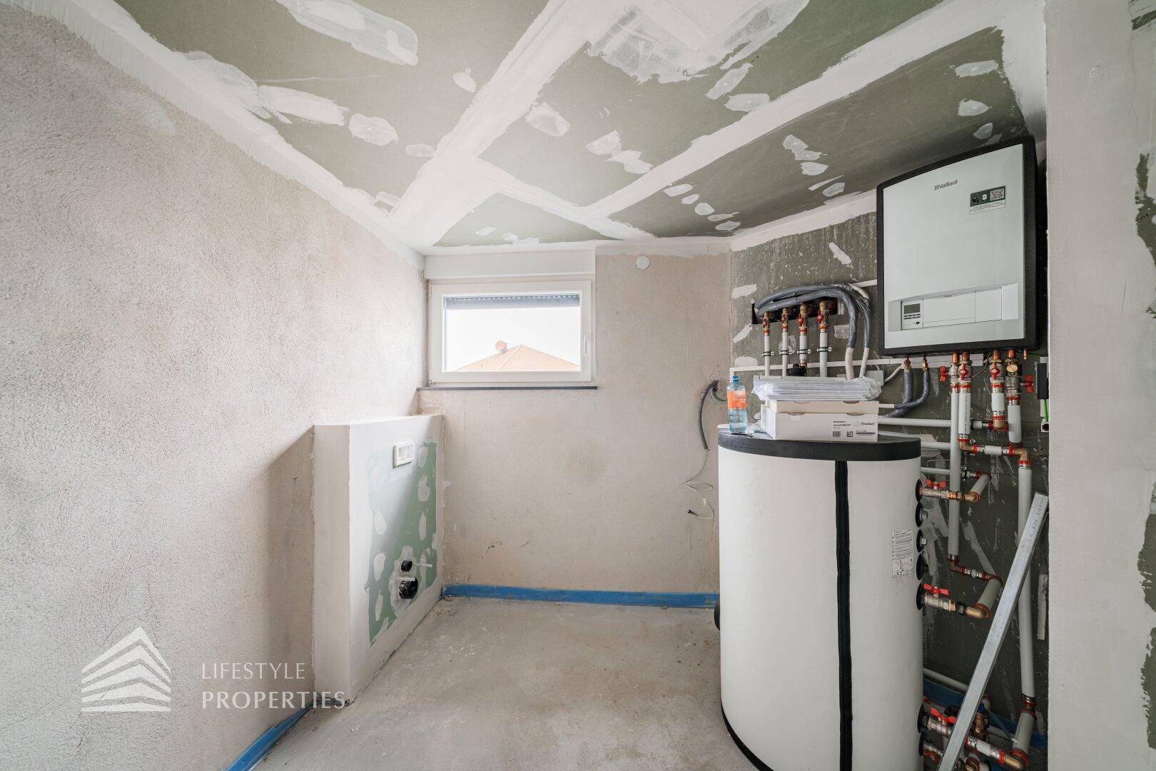 Technikraum mit Heizungsanlage und Warmwasserspeicher, bereit für die Inbetriebnahme.
