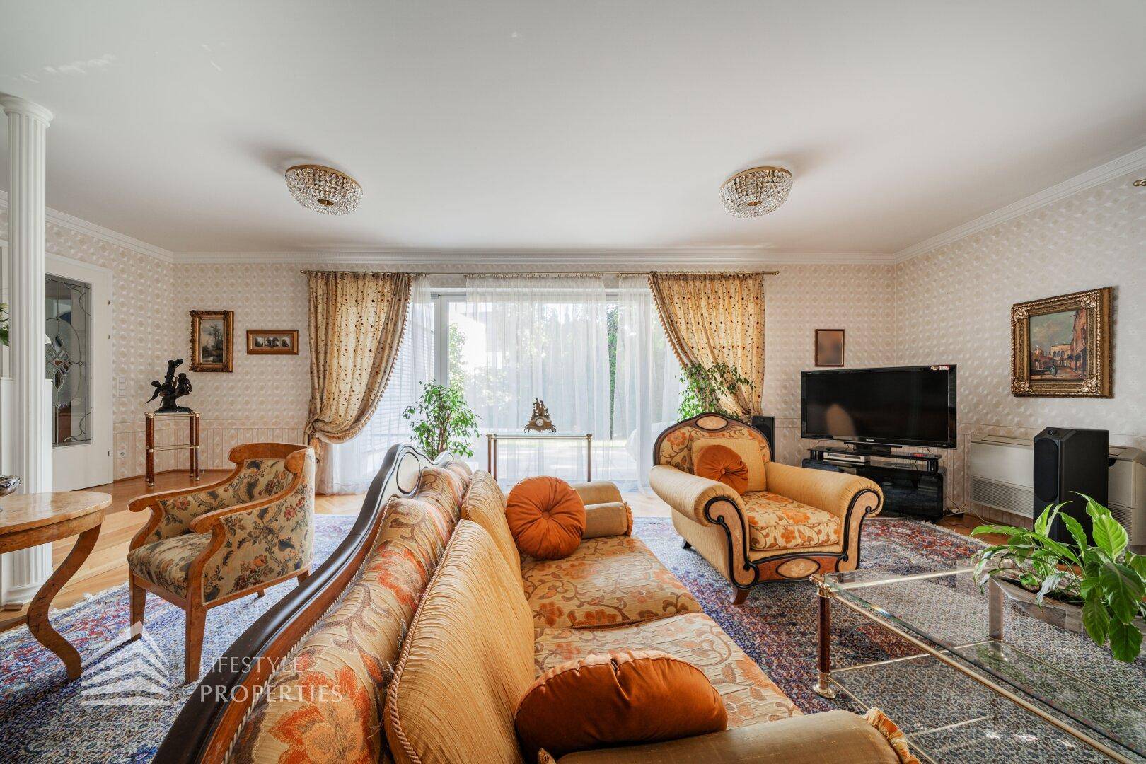 Geräumiges Wohnzimmer mit bequemen Sofas, Teppich und Zugang zu einem sonnigen Außenbereich.