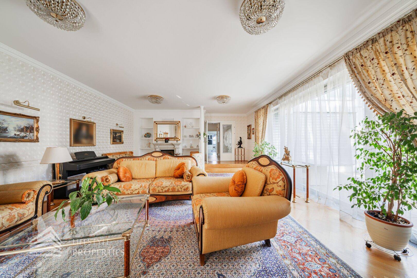 Elegantes Wohnzimmer mit klassischen Möbeln, Parkettboden und großen Fenstern.