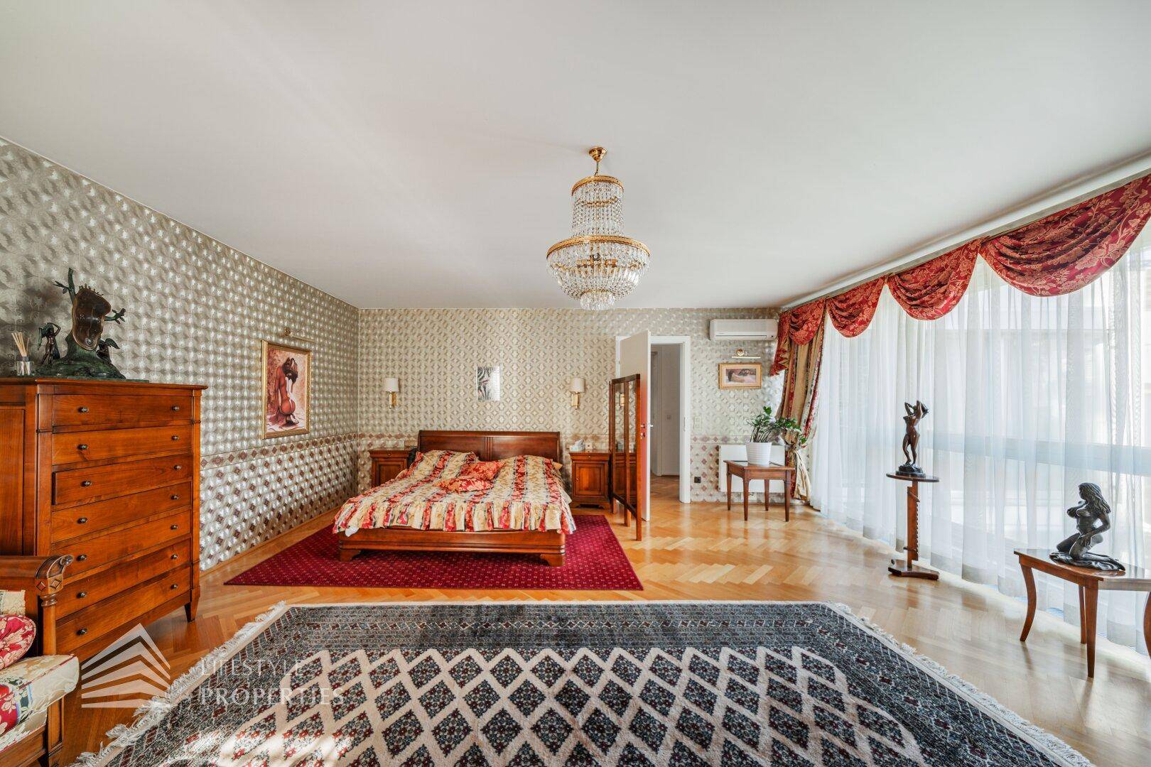 Geräumiges Schlafzimmer mit Doppelbett, Parkettboden und viel Tageslicht.