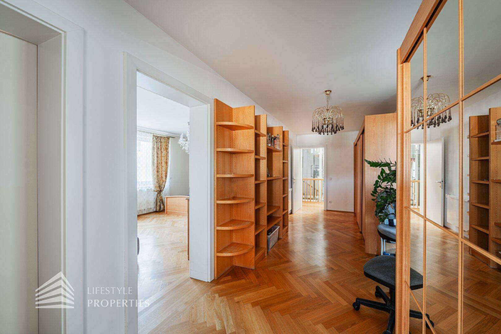 Heller Flur mit Fischgrätparkett, Einbauschränken und Bücherregalen.