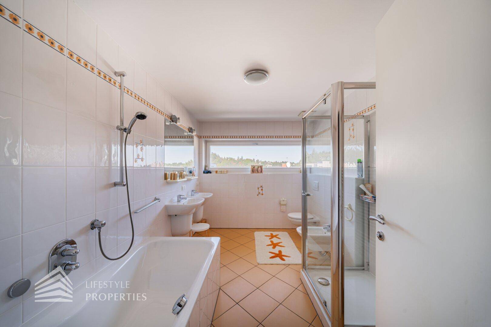 Helles Badezimmer mit Badewanne, Dusche und Fenster für natürliche Belüftung.